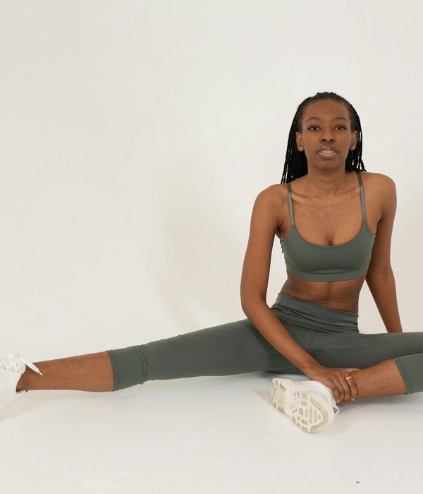 Woman in activewear smiling and stretching in a modern studio.